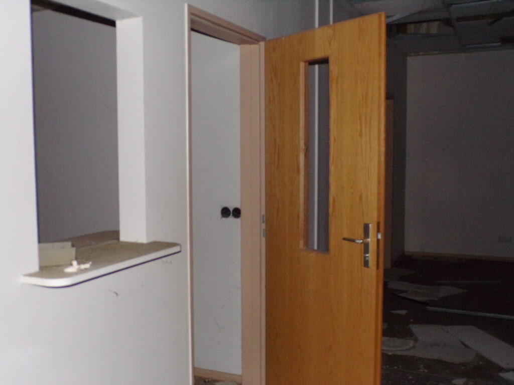 Holztür mit Glasfenster, die in einen Raum führt, mit Wänden und einem offenen Durchgang.